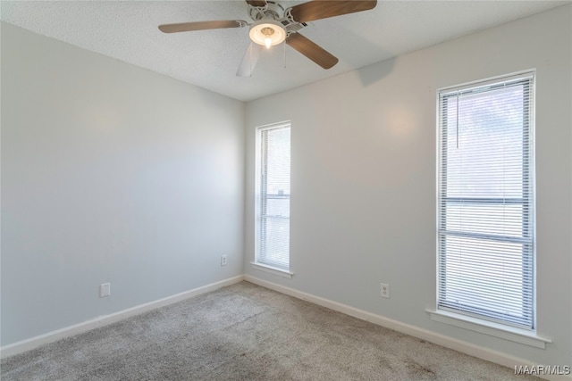 unfurnished room with a textured ceiling, ceiling fan, and light carpet