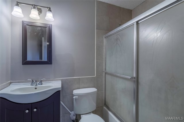 bathroom with vanity, toilet, tile walls, and a textured ceiling