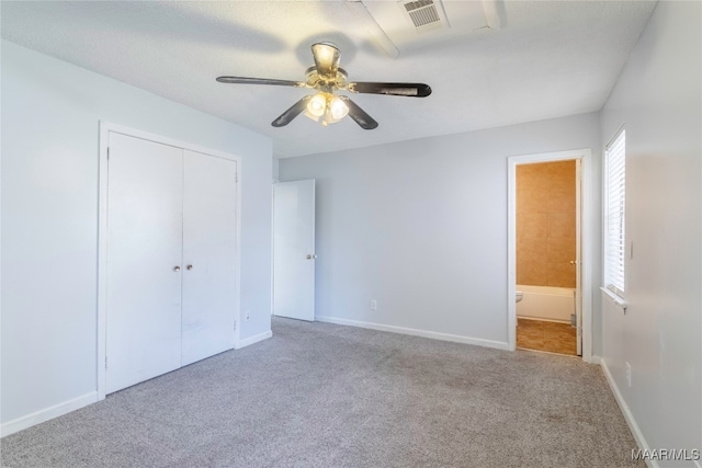 unfurnished bedroom featuring light carpet, connected bathroom, ceiling fan, and a closet