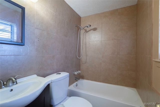 full bathroom featuring a textured ceiling, tile walls, toilet, sink, and tiled shower / bath combo