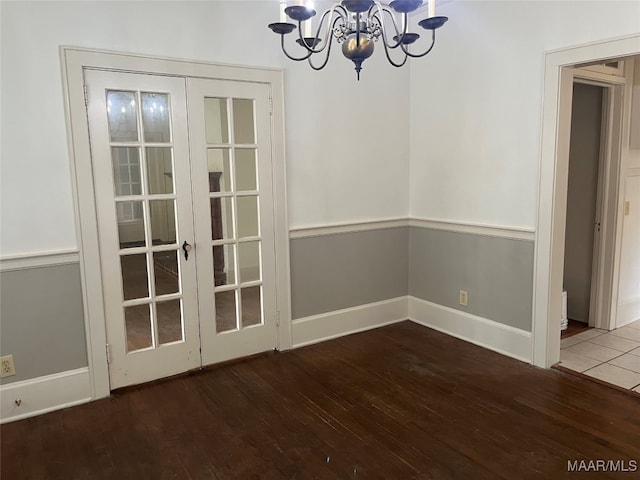 unfurnished dining area featuring french doors, hardwood / wood-style flooring, and a notable chandelier