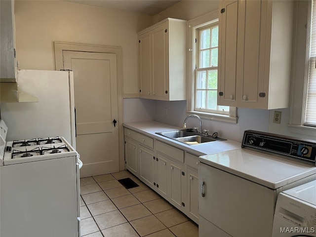 kitchen with white cabinets, light tile patterned floors, white appliances, washer and dryer, and sink