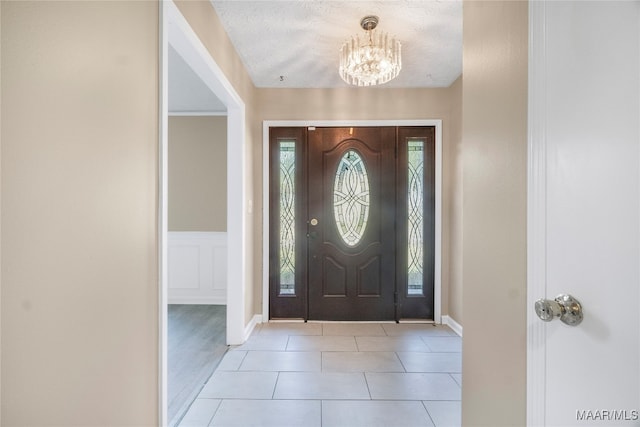 foyer entrance featuring a textured ceiling, a wealth of natural light, light hardwood / wood-style flooring, and an inviting chandelier