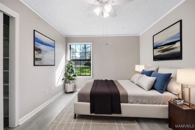 bedroom with a textured ceiling, crown molding, ceiling fan, and hardwood / wood-style floors