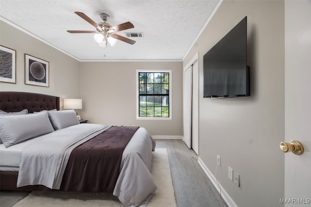 bedroom featuring ornamental molding, a textured ceiling, ceiling fan, and light hardwood / wood-style floors