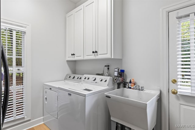 laundry room with cabinet space, a sink, baseboards, and separate washer and dryer