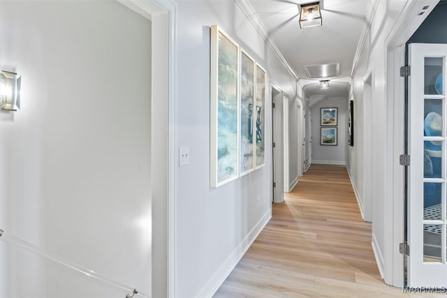 hall featuring light wood-type flooring, baseboards, and crown molding