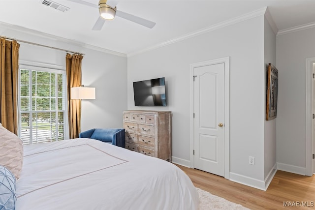 bedroom with baseboards, visible vents, light wood-style flooring, ceiling fan, and crown molding