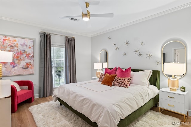 bedroom with ornamental molding, light wood-type flooring, visible vents, and ceiling fan