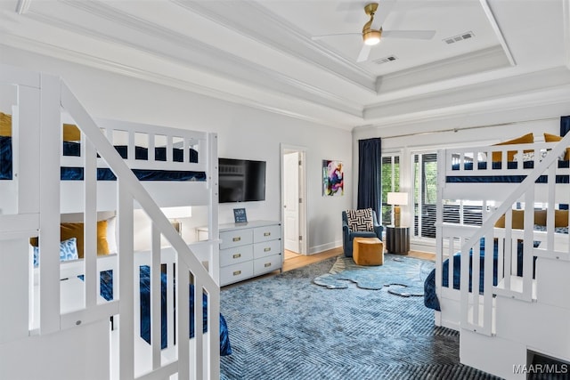 bedroom with visible vents, a raised ceiling, crown molding, and wood finished floors