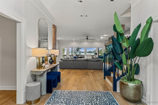 living room featuring stairs, ceiling fan, light wood-type flooring, and visible vents