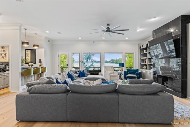 living area with recessed lighting, a fireplace, a wealth of natural light, and light wood-style floors