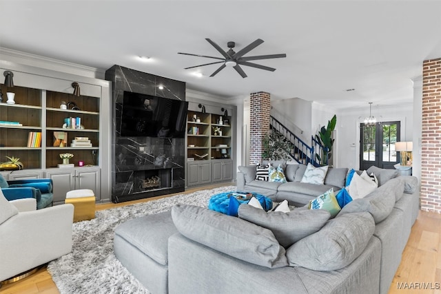 living room with light wood-type flooring, stairs, a fireplace, and crown molding