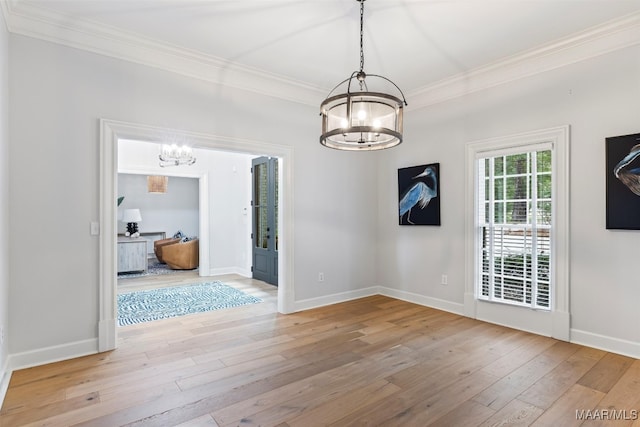 unfurnished dining area featuring light wood-type flooring, crown molding, and a notable chandelier