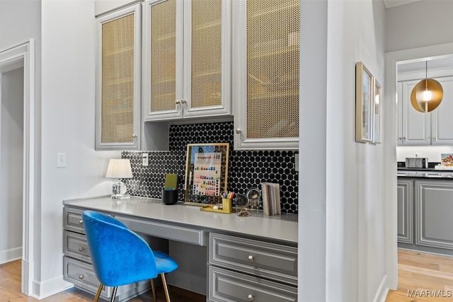 office space with light wood-style floors, built in desk, and baseboards