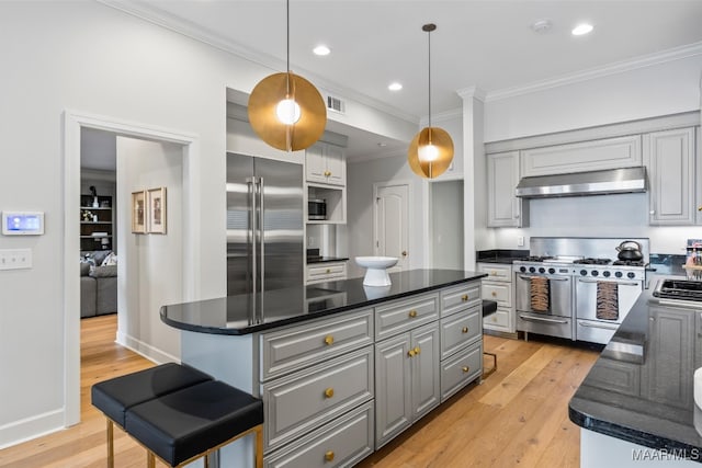 kitchen featuring visible vents, high end appliances, a center island, crown molding, and under cabinet range hood