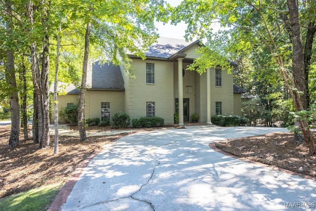 neoclassical home with roof with shingles and brick siding