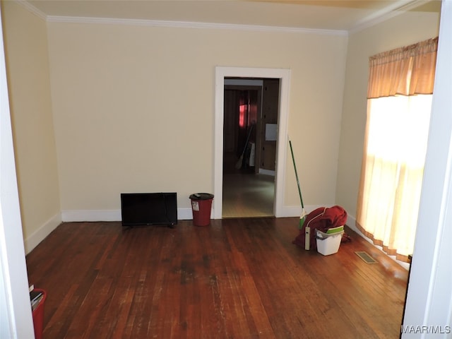 empty room featuring crown molding, a healthy amount of sunlight, and dark hardwood / wood-style flooring