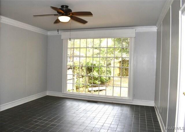 empty room featuring ceiling fan, ornamental molding, and dark tile patterned floors