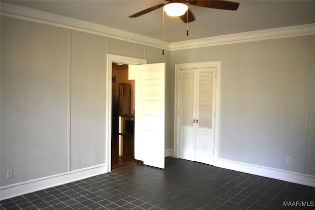 unfurnished bedroom with crown molding, dark tile patterned flooring, ceiling fan, and a closet