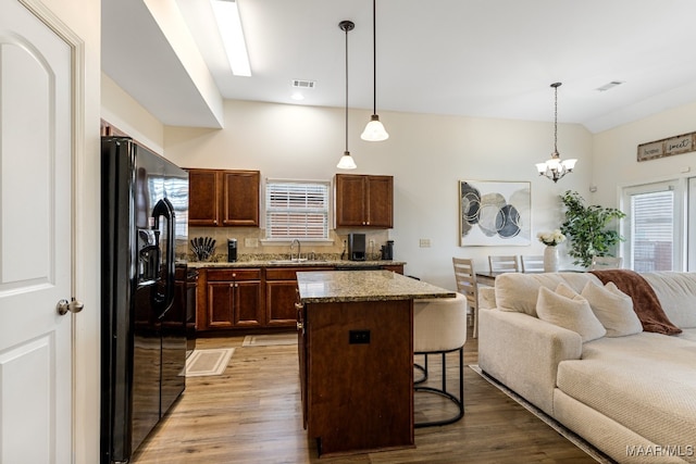 kitchen with a center island, sink, light hardwood / wood-style flooring, and black fridge