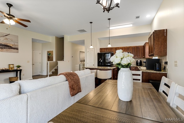 dining space with ceiling fan with notable chandelier