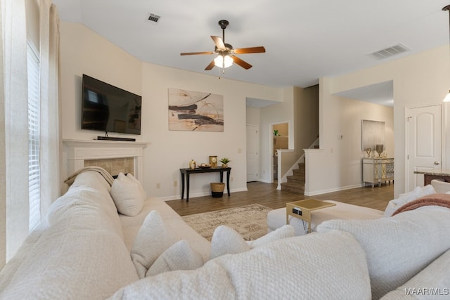 living room with light wood-type flooring, ceiling fan, and a fireplace