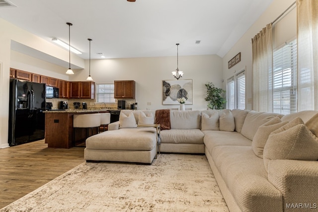 living room featuring a wealth of natural light, a chandelier, sink, and light hardwood / wood-style floors