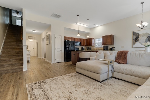 living room featuring an inviting chandelier, sink, and light hardwood / wood-style floors