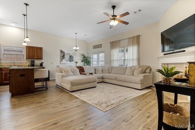 living room with ceiling fan with notable chandelier and light hardwood / wood-style floors