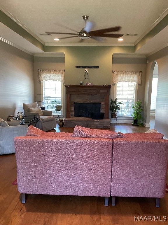 living room with wood-type flooring, ornamental molding, ceiling fan, and a healthy amount of sunlight