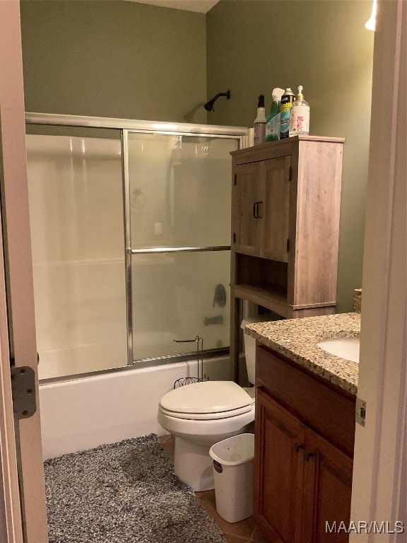 full bathroom with tile patterned floors, combined bath / shower with glass door, vanity, and toilet