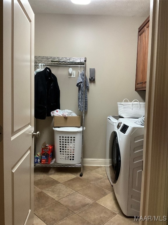 laundry room featuring cabinets, light tile patterned floors, and washer and dryer