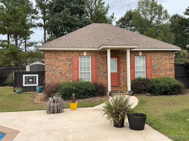 view of front of house with a storage unit, a front lawn, and a patio