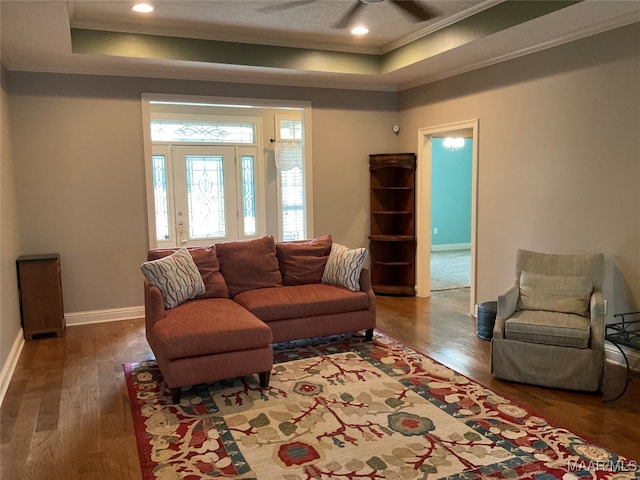 living room with ornamental molding, dark hardwood / wood-style flooring, and a tray ceiling