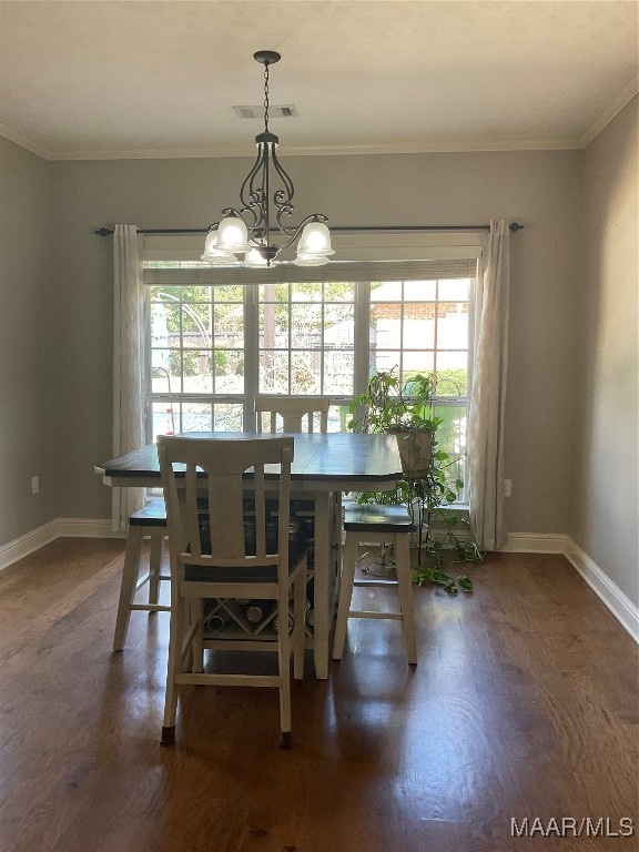 dining room with an inviting chandelier, crown molding, and dark hardwood / wood-style flooring