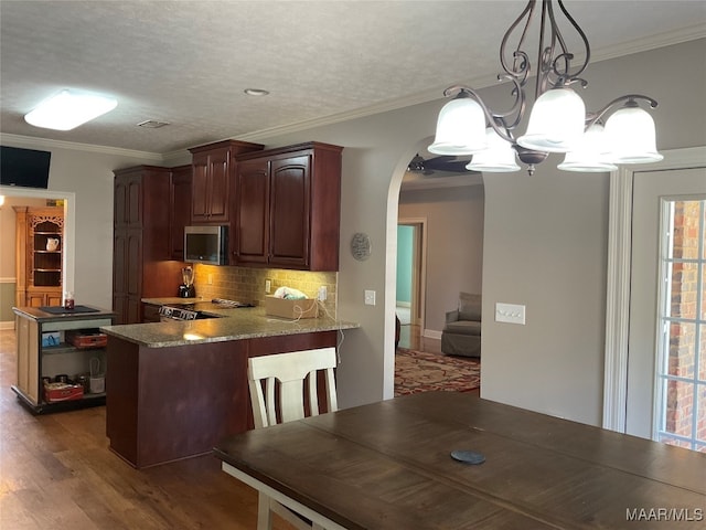 kitchen featuring hanging light fixtures, dark wood-type flooring, light stone counters, kitchen peninsula, and an inviting chandelier