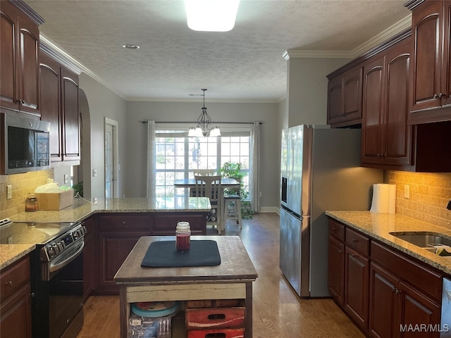 kitchen with an inviting chandelier, stainless steel appliances, light hardwood / wood-style floors, and a kitchen island