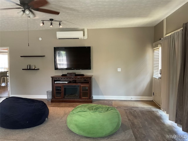 living room with ceiling fan, a textured ceiling, hardwood / wood-style floors, and a wall mounted AC