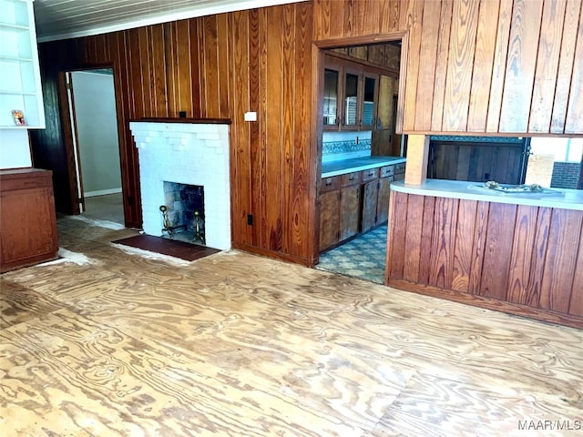 unfurnished living room with crown molding, wood walls, and a fireplace