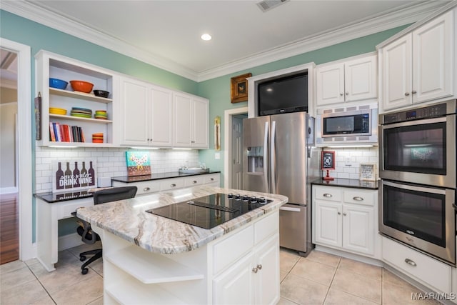 kitchen with appliances with stainless steel finishes, light tile patterned flooring, a kitchen island, and white cabinets