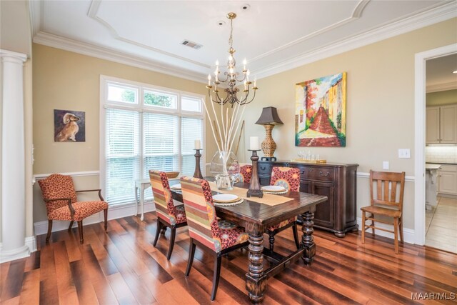 dining area with ornamental molding, wood-type flooring, decorative columns, and a notable chandelier