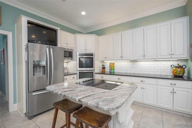 kitchen featuring light tile patterned flooring, a kitchen island, stainless steel appliances, and white cabinets