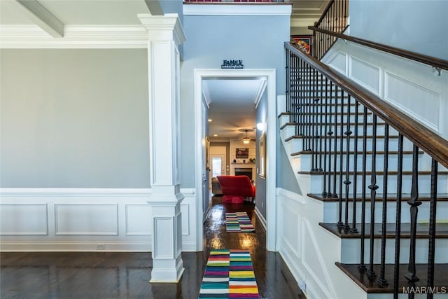 staircase featuring a fireplace, ornate columns, and ornamental molding