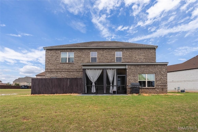 rear view of property featuring a yard and a sunroom