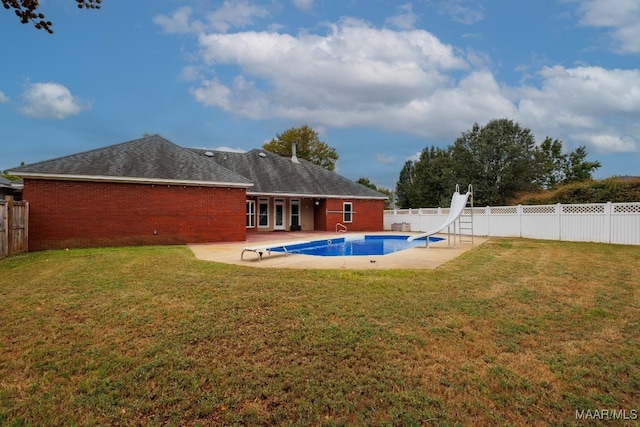 view of swimming pool with a water slide, a yard, and a patio