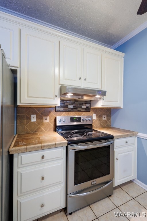 kitchen featuring light tile patterned floors, stainless steel appliances, ornamental molding, decorative backsplash, and white cabinetry