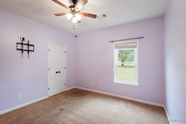 carpeted spare room featuring a textured ceiling and ceiling fan