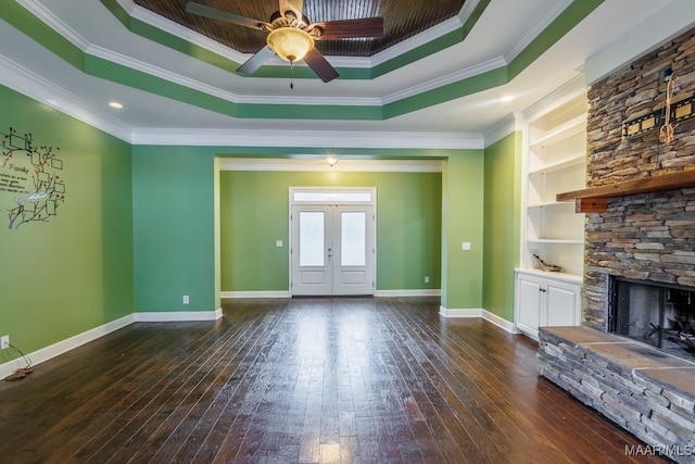 unfurnished living room with a raised ceiling, a fireplace, dark wood-type flooring, ornamental molding, and ceiling fan