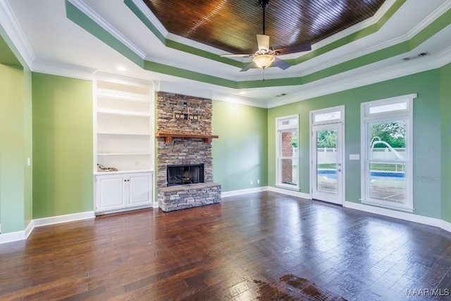 unfurnished living room with ornamental molding, ceiling fan, a stone fireplace, dark hardwood / wood-style floors, and a raised ceiling